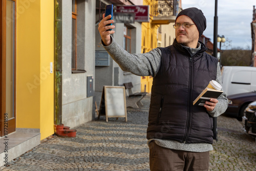 A man with a smartphone walking through an autumn city.