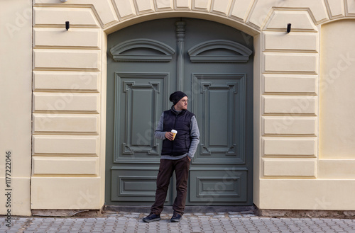 Obraz na płótnie A man with a cup of coffee walking through an autumn city. w salonie