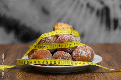 Dieta a słodycze, pączki posypane cukrem i centymetr krawiecki  photo