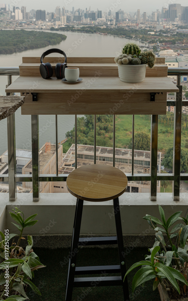 Decorated balcony with Adjustable balcony bar table and wood chair. Relaxation area on Condominium balcony overlooking river view, Cozy space with Ear headphones,Tea cup and Cactus pot on Folding deck