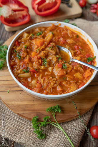 Healthy vegan vegetable, red lentil soup with tomatoes, peppers, cabbage, carrots, onions and garlic on a plate fresh and homemade cooked.