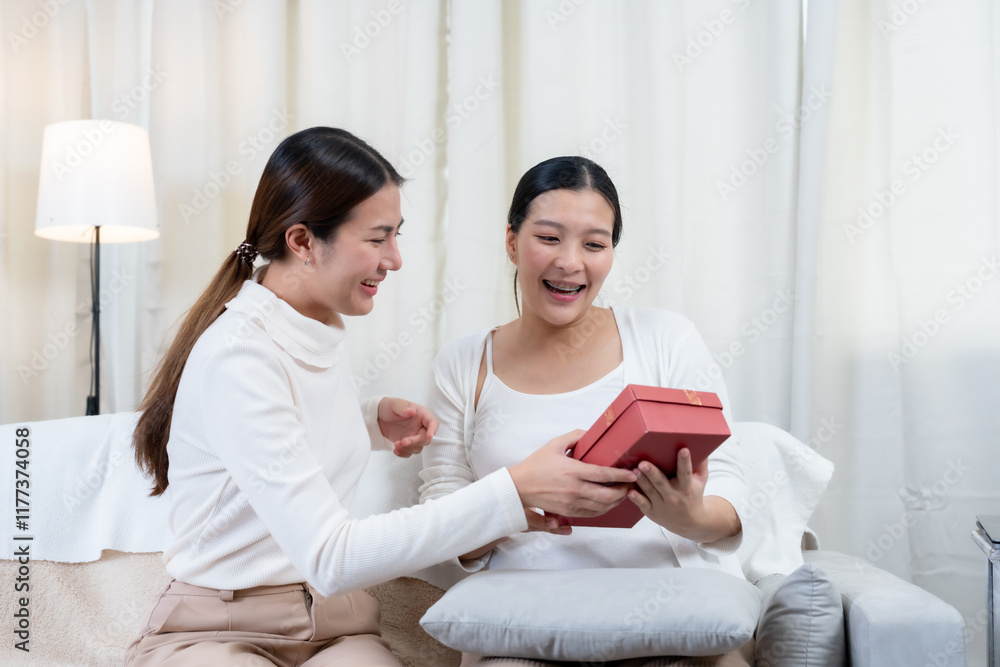 Asian pregnant woman working on a laptop while sitting on a comfortable sofa, holding a glass of orange juice nearby, showing a modern lifestyle and work-life balance during pregnancy. Asian pregnant woman working on a laptop while sitting on a comfortable sofa, holding a glass of orange juice nearby, showing a modern lifestyle and work-life balance during pregnancy.