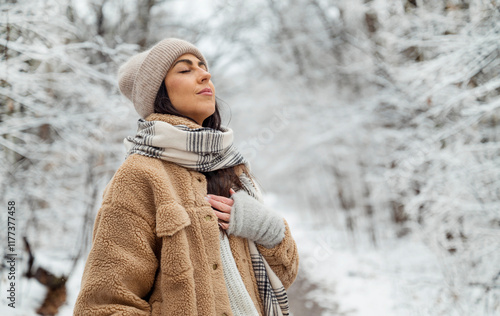 Beautiful  woman breathing fresh air in a snowy forest. Winter time