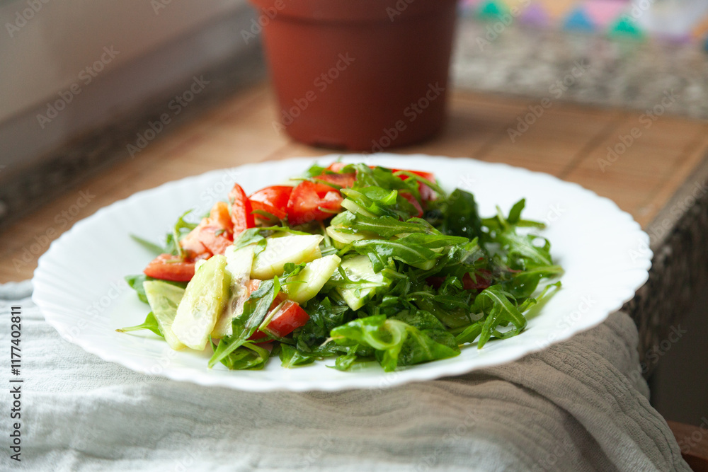 Fresh salad with tomatoes, cucumbers, and arugula on a white plate. Healthy and delicious!