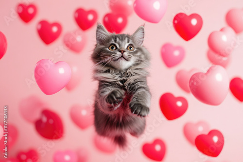 Cute kitten playing with floating heart balloons for Valentine's Day celebration photo