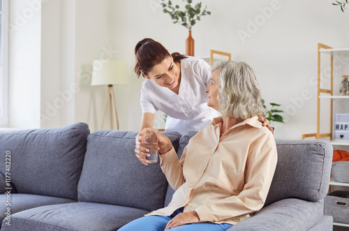 Caring kind female medical nurse giving glass of water to senior patient, assisted living caregiver supports, nursing home healthcare help, elder people rehabilitation or healing during retirement