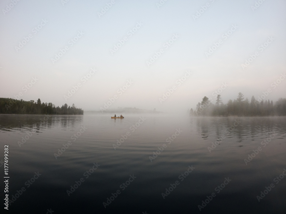 Tandem canoe paddling in a misty morning on the lake in the Boundary Waters (BWCA) Tandem canoe paddling in a misty morning on the lake in the Boundary Waters (BWCA)