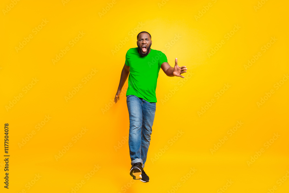 Full length body size photo of angry furious yelling commanding black man wearing jeans denim screaming into camera while isolated with yellow vivid background Full length body size photo of angry furious yelling commanding black man wearing jeans denim screaming into camera while isolated with yellow vivid background