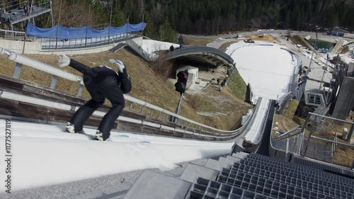 Ski jumper running down the ski jump, jumping and landing on the landing slope, high angle shot. Hills winter tournament concept.