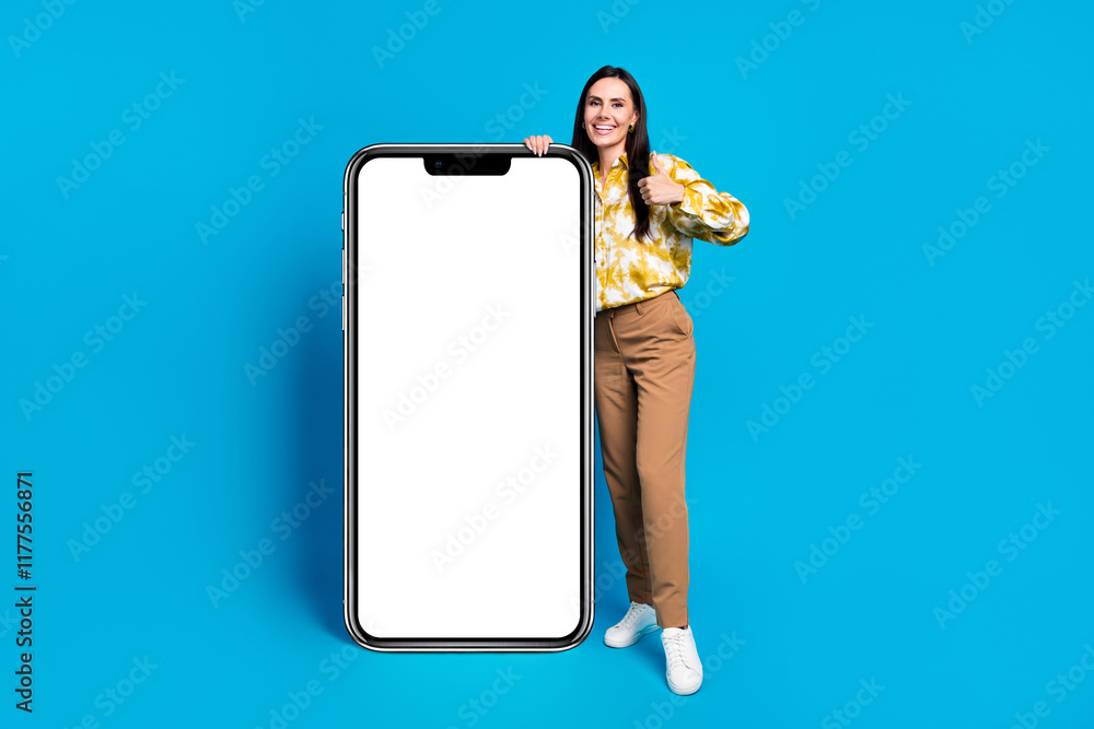 Photo of adorable elegant woman wear trendy clothes hold display poster thumb up empty space isolated on blue color background