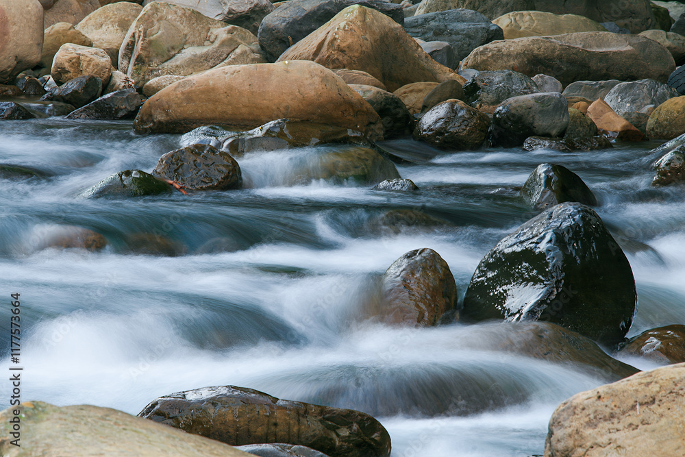 A serene river flowing over smooth rocks. The water appears silky due to long exposure, creating a tranquil scene. Wulai District, New Taipei City, Taiwan. A serene river flowing over smooth rocks. The water appears silky due to long exposure, creating a tranquil scene. Wulai District, New Taipei City, Taiwan.
