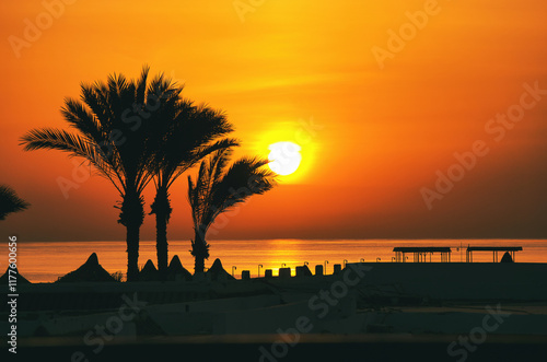 Fantastic sunrise in Marsa Alam over the Red Sea. Visible palm trees, beach umbrellas, typical hotel buildings. Egypt, Marsa Alam 2024