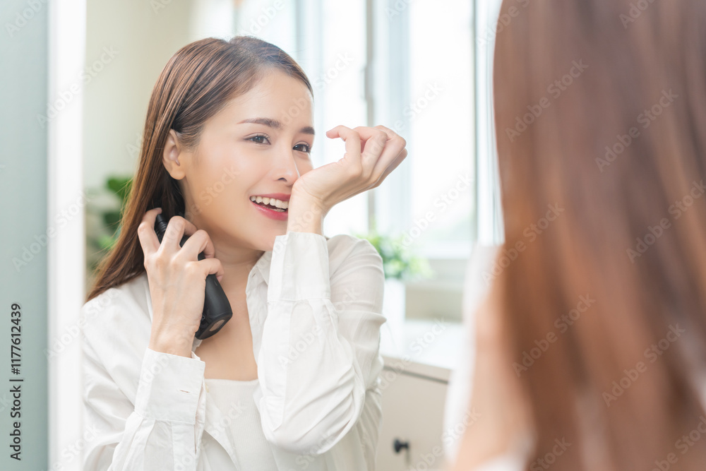 Perfume of essential aroma, beauty concept. attractive perfect asian young woman holding perfume bottle, using spray and applying fragrance, smelling scent at wrist on body reflect of mirror at home. Perfume of essential aroma, beauty concept. attractive perfect asian young woman holding perfume bottle, using spray and applying fragrance, smelling scent at wrist on body reflect of mirror at home.