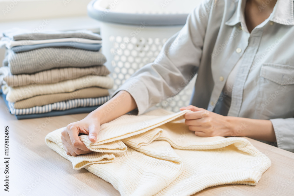 Housewife working asian young woman, girl hand in many folding freshly white sweaters or dressing on table after washing clean up clothes and drying, making on table at home. Laundry maid in household Housewife working asian young woman, girl hand in many folding freshly white sweaters or dressing on table after washing clean up clothes and drying, making on table at home. Laundry maid in household