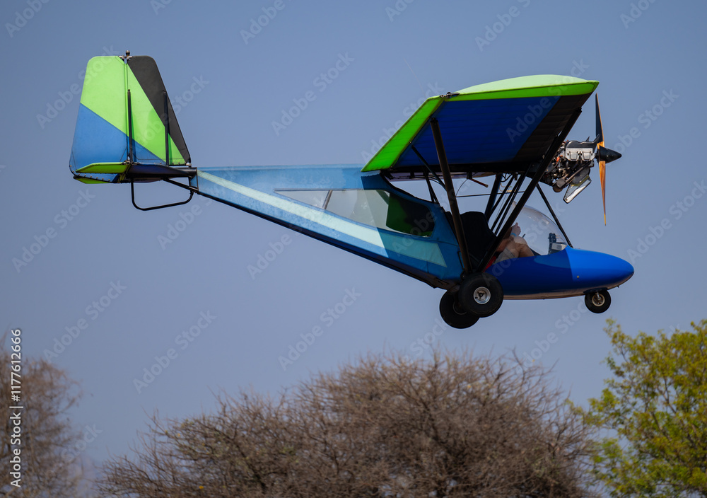 blau grünes Ultraleichtflugzeug beim Start auf der Landebahn und Startbahn in Hoedspruit Südafrika