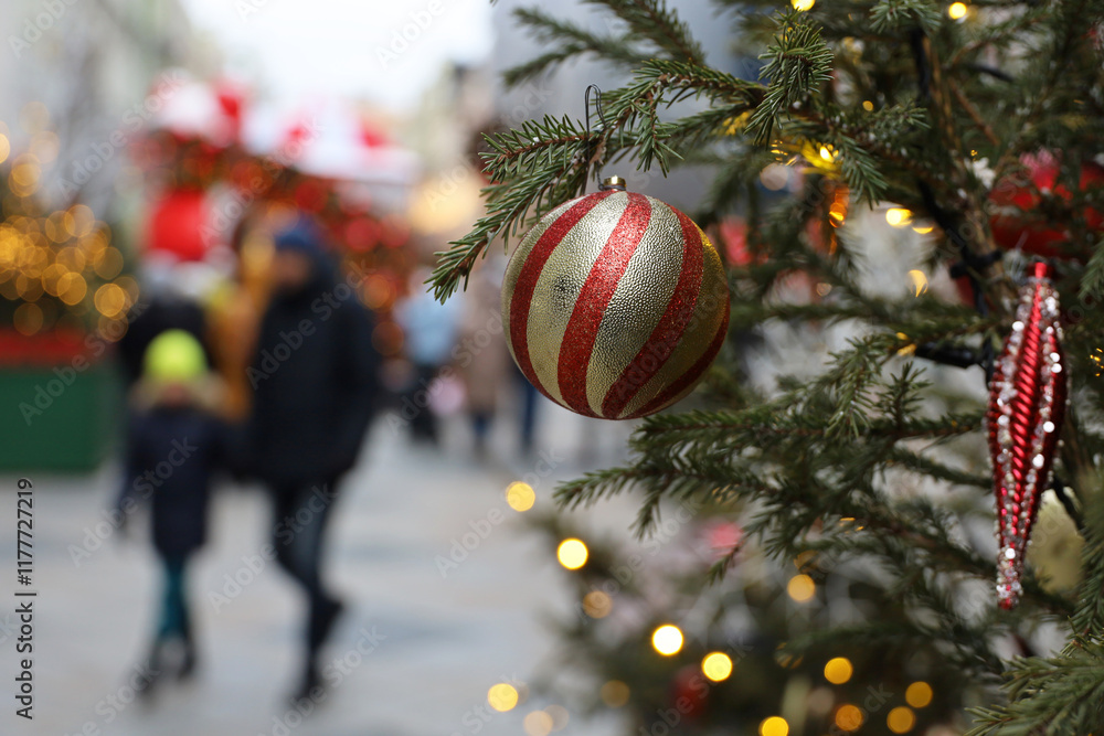Φωτογραφία New Year celebration in city, toy ball on a fir branch on a street on blurred ba
