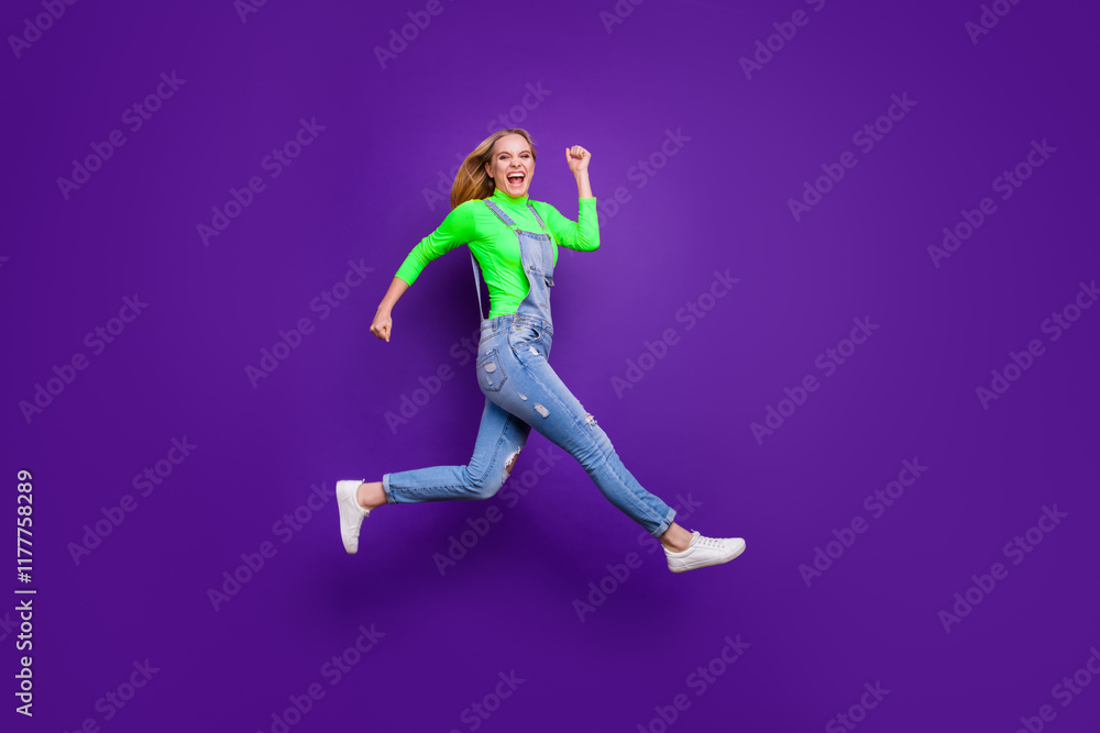 Full length photo of cheerful teenager running screaming wearing yellow turtleneck denim jeans overalls isolated over violet purple background Full length photo of cheerful teenager running screaming wearing yellow turtleneck denim jeans overalls isolated over violet purple background