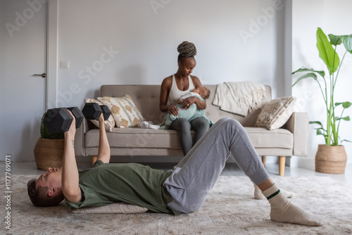 Father working out while mother lulling baby photo