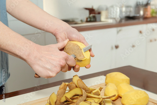 closeup of woman peeling raw potatoes in the kitchen photo