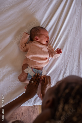 Mother changing diaper of crying baby