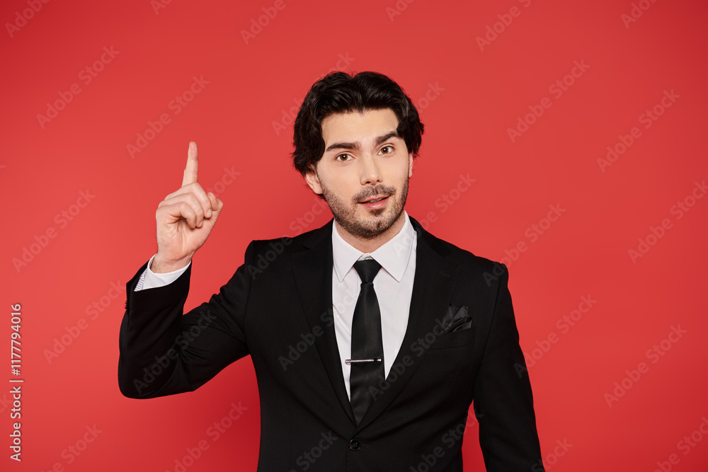 Young handsome man in tailored suit gesturing confidently against vibrant red backdrop Young handsome man in tailored suit gesturing confidently against vibrant red backdrop