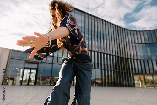 A dancer poses dramatically outdoors in front of a modern building photo