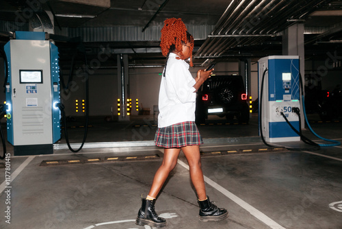 Black woman walking in a parking garage with electric car chargers photo