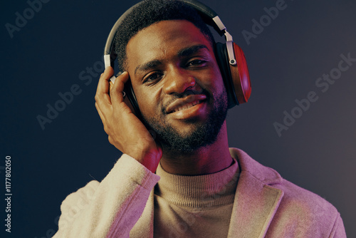 A smiling male model wearing headphones, showcasing a stylish outfit against a vibrant, colorful background, perfect for music and lifestyle themes photo