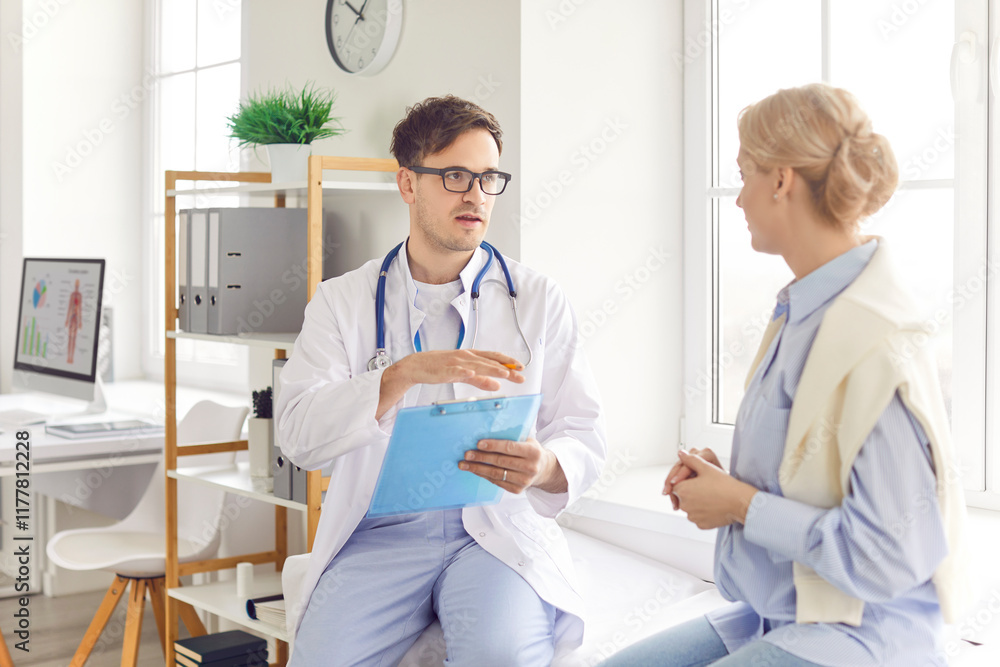 Young woman patient sitting on couch in medical office listening to friendly male doctor therapist holding report file with appointment and giving consultation during medical examination in clinic. Young woman patient sitting on couch in medical office listening to friendly male doctor therapist holding report file with appointment and giving consultation during medical examination in clinic.