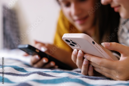 Focus on smartphone in hands of cropped girl near girlfriend on bed photo