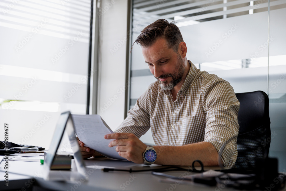 Male manager reading document at desk Male manager reading document at desk