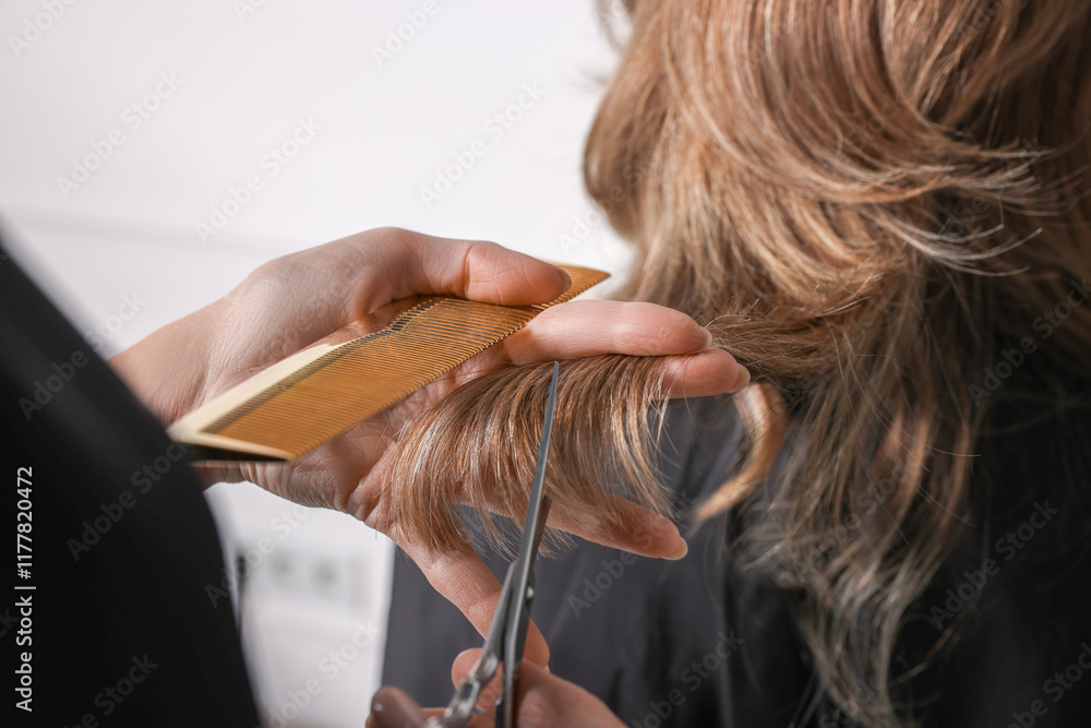 Fototapeta premium Hairdresser cutting client's hair with scissors in salon, closeup