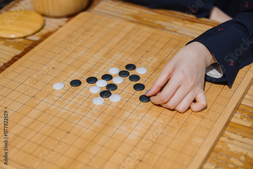 Hand Playing Go on Wooden Board photo