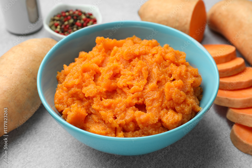 Tasty mashed sweet potato in bowl and fresh vegetables on gray table, closeup Tasty mashed sweet potato in bowl and fresh vegetables on gray table, closeup