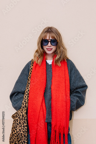 A young woman poses confidently against a plain wall in winter photo