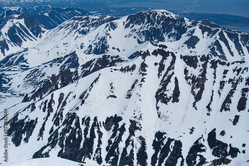 Aerial view of the snow-covered mountains in the Magadan region of Russia. Winter landscape of the mountains. Air travel to the far north of Russia. Nature of Siberia and Russian Far East. photo