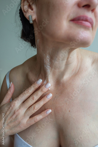 Portrait of mature woman applying cream on her neck photo