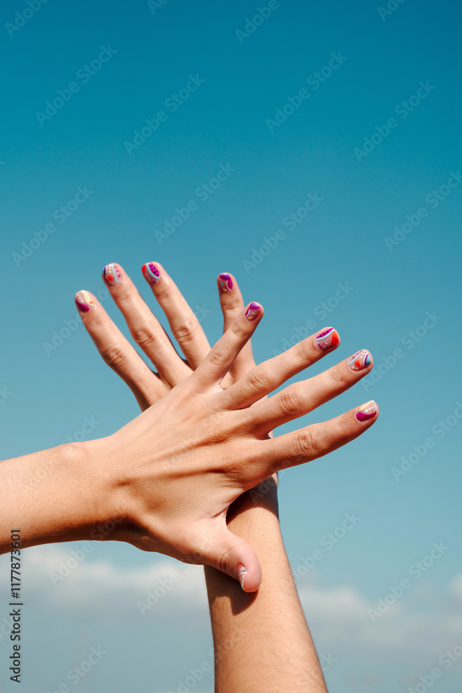Hand manicure with colorful nails over blue sky Hand manicure with colorful nails over blue sky