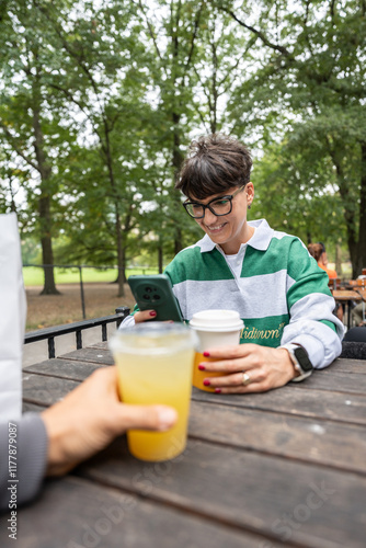 Woman using smartphone and drinking juice in manhattan park photo