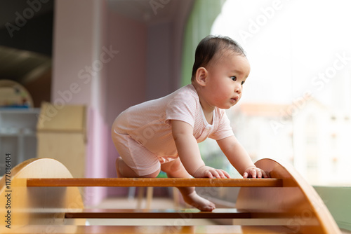 Adorable Baby Crawling on Wooden Climbing Structure Indoors photo