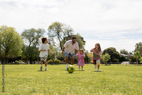 Dad with his kids playing soccer in a park
