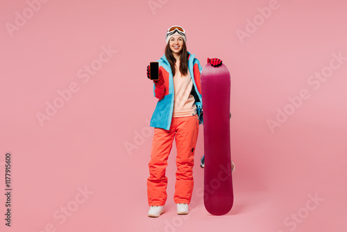 Full body young woman wear warm blue jacket ski goggles mask spend weekend winter season in mountains hold snowboard use blank screen mobile cell phone isolated on plain pink background Hobby concept