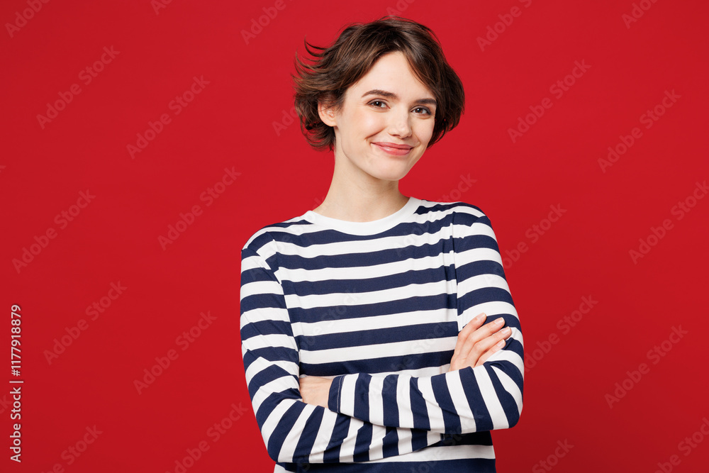 Young smiling cheerful satisfied happy woman she wear blue striped sweatshirt casual clothes hold hands crossed folded look camera isolated on plain red background studio portrait. Lifestyle concept.