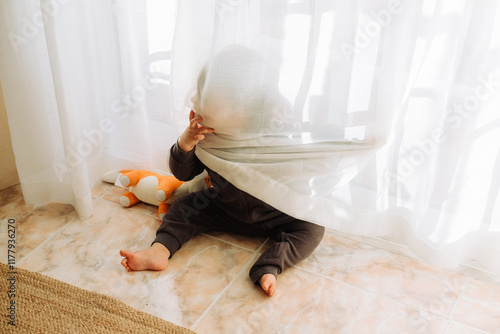 Child hiding and playing behind sheer curtains photo