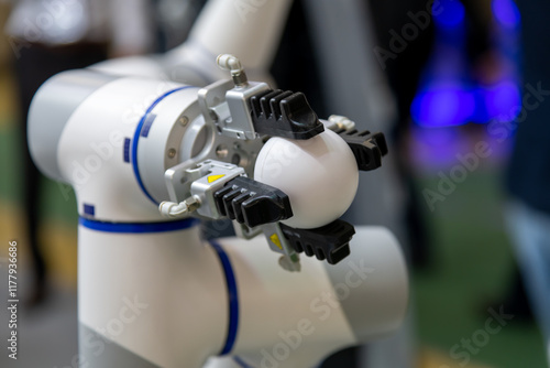 Slika na platnu Close-up view of modern white and grey robotic arm manipulator holding white ball in industrial building