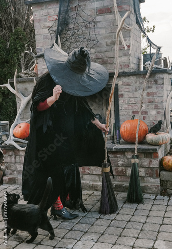 witch looks down at her black cat while holding her broom photo