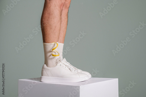 Man Wearing White Sneakers and Colorful Socks on Pedestal photo