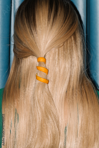 Creative Hairstyle With Orange Peel Accessory Against Blue Curta photo