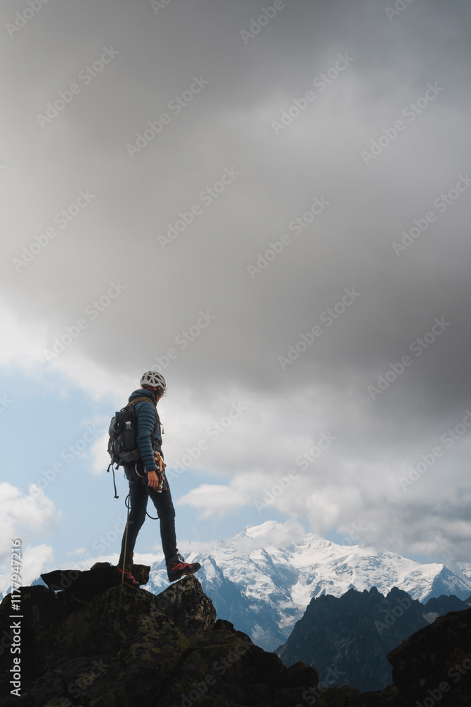Climber standing confidently on a rocky summit in the French Alps under dramatic clouds. Climber standing confidently on a rocky summit in the French Alps under dramatic clouds.