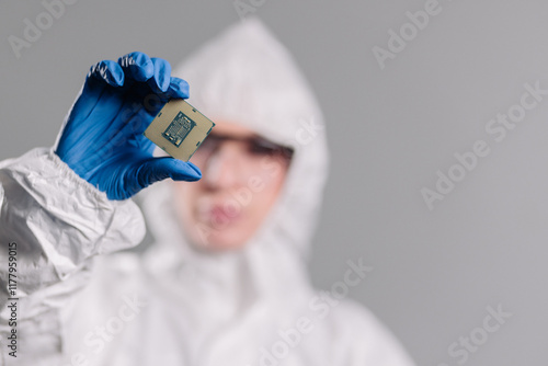 In a high-tech electronics factory, a design engineer in a sterile coverall examines a microchip with gloves, perfect for showcasing innovation, precision engineering, and advanced manufacturing. photo